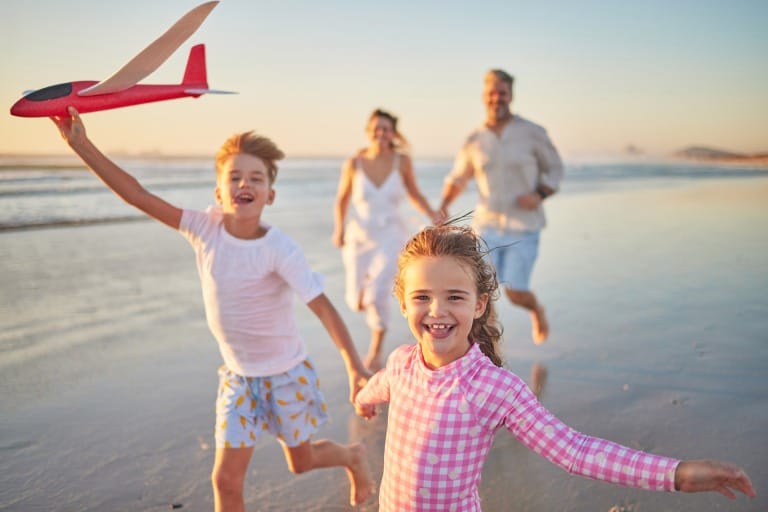 Family running on beach as the sun sets.